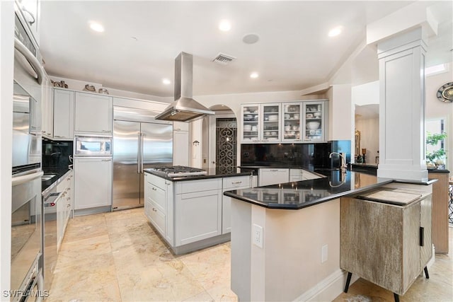 kitchen with sink, built in appliances, a kitchen island, island exhaust hood, and white cabinets