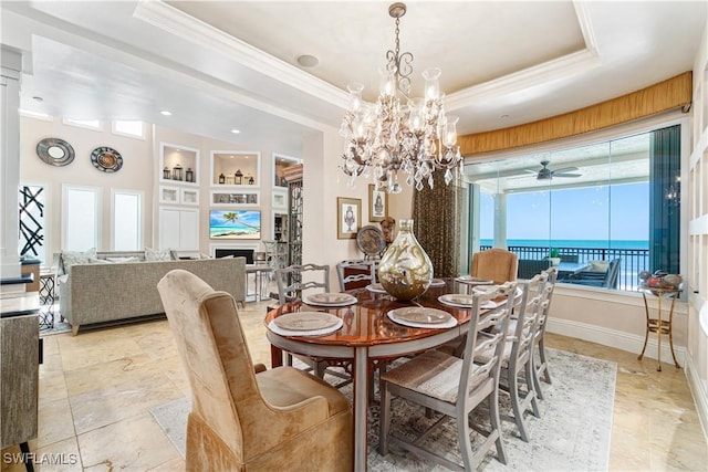 dining room featuring a raised ceiling, crown molding, a water view, and built in features