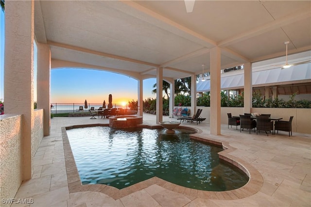 pool at dusk with a patio and a water view