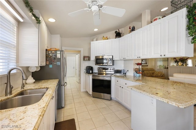 kitchen featuring light stone counters, sink, stainless steel appliances, and white cabinets