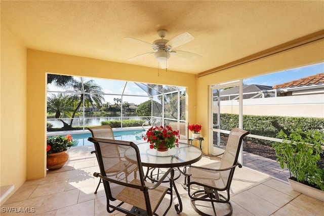 sunroom featuring a water view and ceiling fan