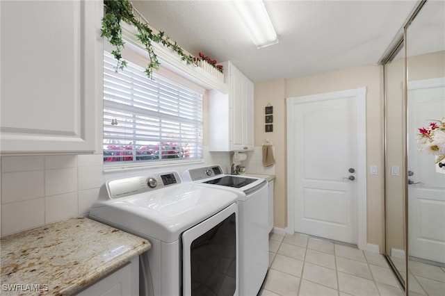 laundry area with cabinets, light tile patterned floors, and washing machine and clothes dryer