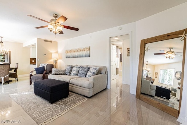 living area with ceiling fan with notable chandelier, visible vents, and baseboards