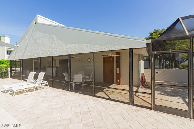 rear view of house with a lanai, stucco siding, a ceiling fan, and a patio