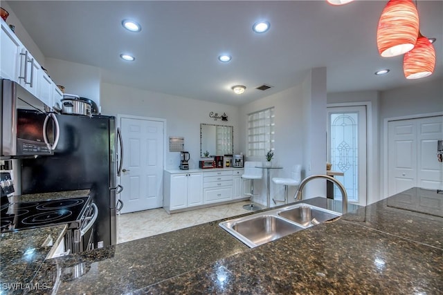 kitchen featuring white cabinetry, stainless steel appliances, sink, and dark stone counters