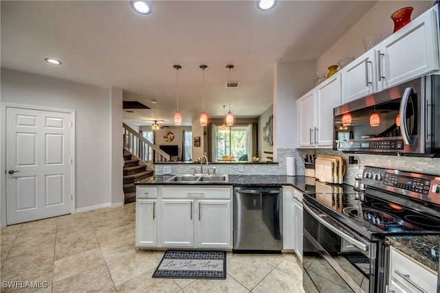 kitchen featuring pendant lighting, sink, dark stone countertops, stainless steel appliances, and white cabinets