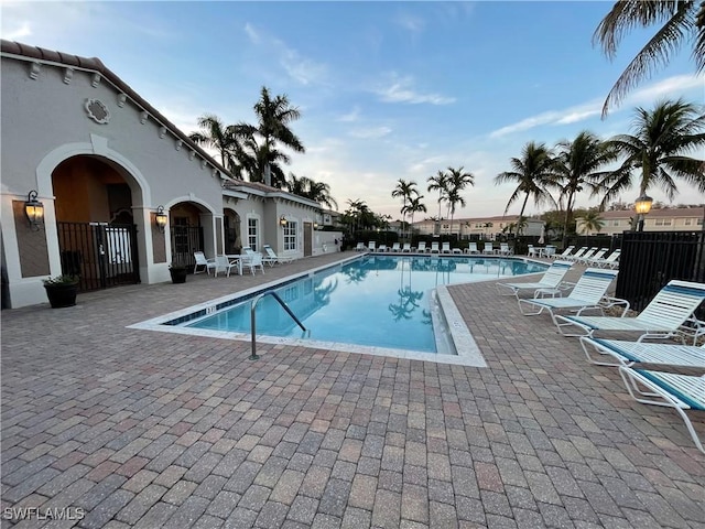 pool at dusk featuring a patio area