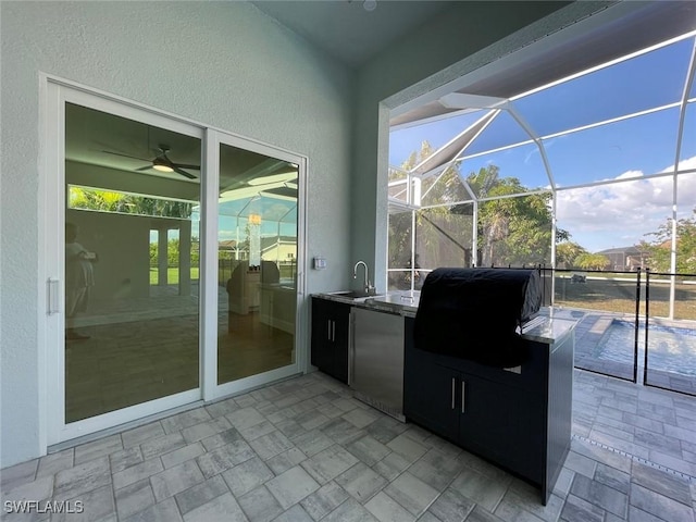 view of patio / terrace featuring a grill, sink, exterior kitchen, ceiling fan, and glass enclosure