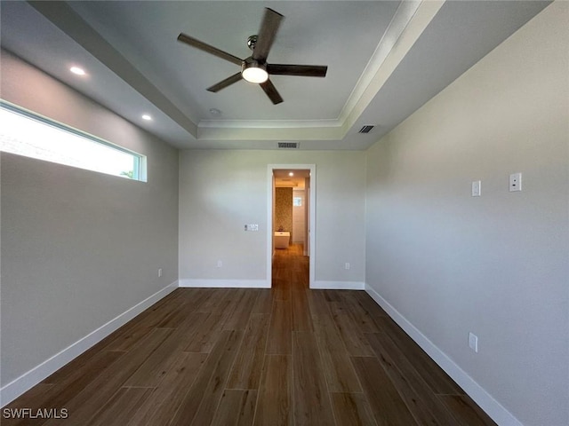 spare room featuring a raised ceiling, dark wood-type flooring, and ceiling fan