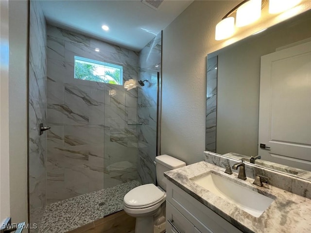 bathroom featuring vanity, tiled shower, and toilet