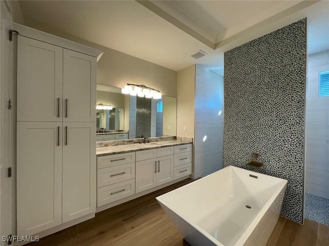 bathroom with wood-type flooring, separate shower and tub, vanity, and tile walls