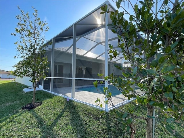 view of home's exterior with a lawn, a patio, and glass enclosure