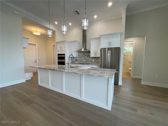 kitchen with white cabinetry, sink, hanging light fixtures, stainless steel appliances, and wall chimney range hood