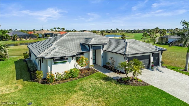 single story home with a garage, a front yard, and a water view