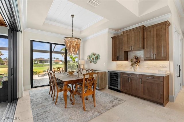 dining room with wine cooler, a notable chandelier, a tray ceiling, and ornamental molding