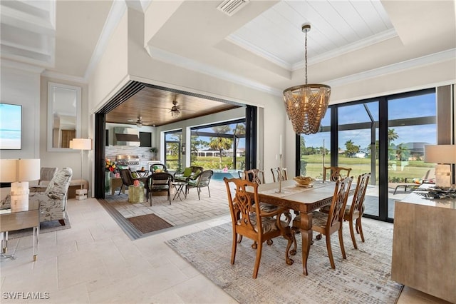 dining space with crown molding, a tray ceiling, and a chandelier