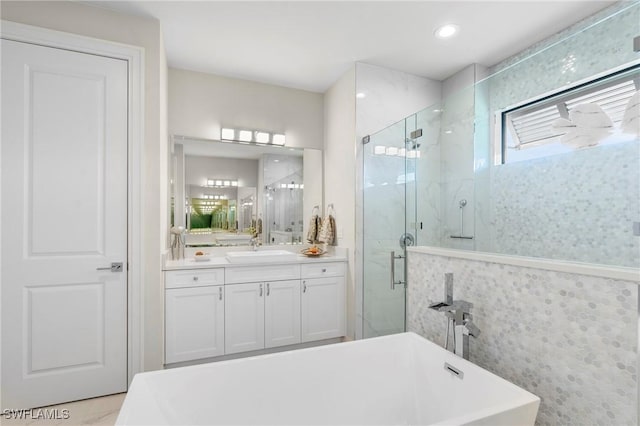 bathroom with vanity and shower with separate bathtub