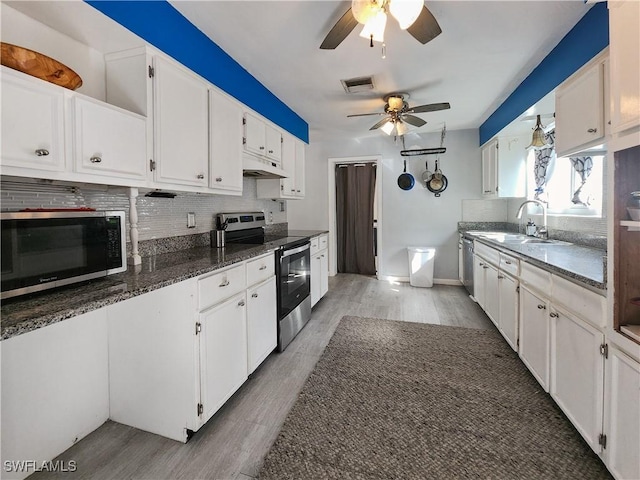 kitchen with sink, dark stone countertops, stainless steel appliances, white cabinets, and decorative backsplash