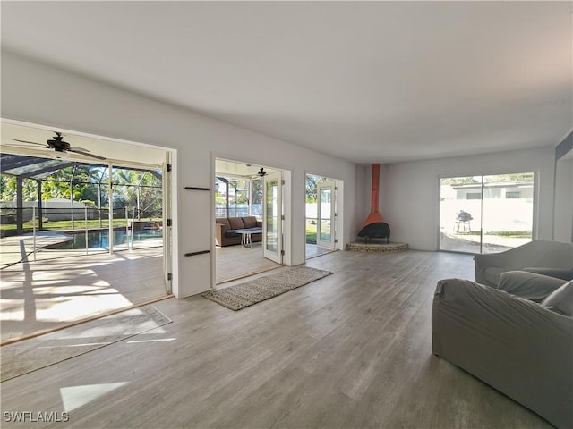 living room with ceiling fan, wood-type flooring, and a wood stove