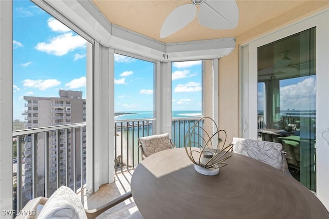 sunroom with a water view and ceiling fan