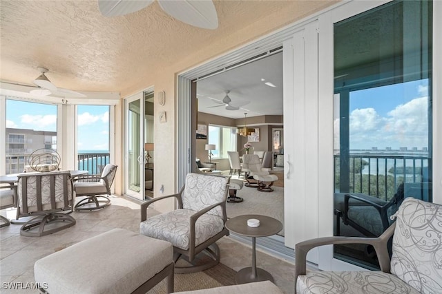 sunroom featuring ceiling fan and a water view