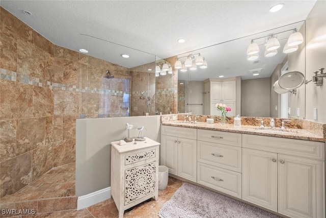 bathroom featuring vanity, a textured ceiling, and a tile shower