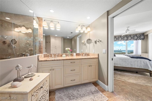 bathroom with vanity, a tile shower, a textured ceiling, and ceiling fan