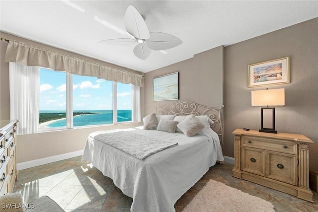 bedroom with a water view and ceiling fan