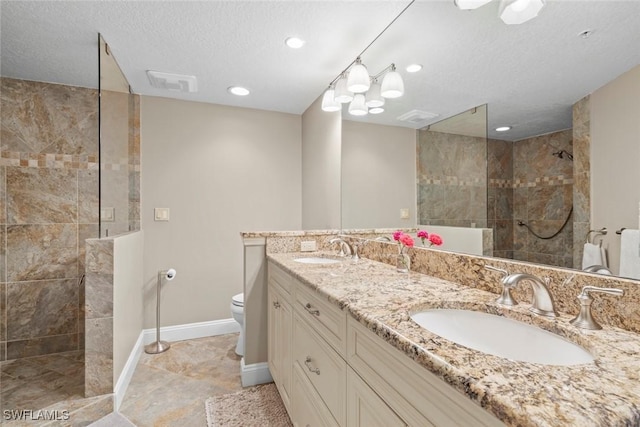 bathroom featuring vanity, toilet, a textured ceiling, and a tile shower