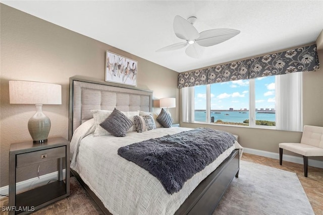 bedroom with a water view and ceiling fan