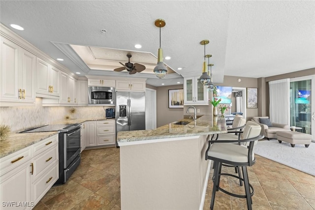 kitchen featuring sink, white cabinetry, hanging light fixtures, appliances with stainless steel finishes, and a tray ceiling