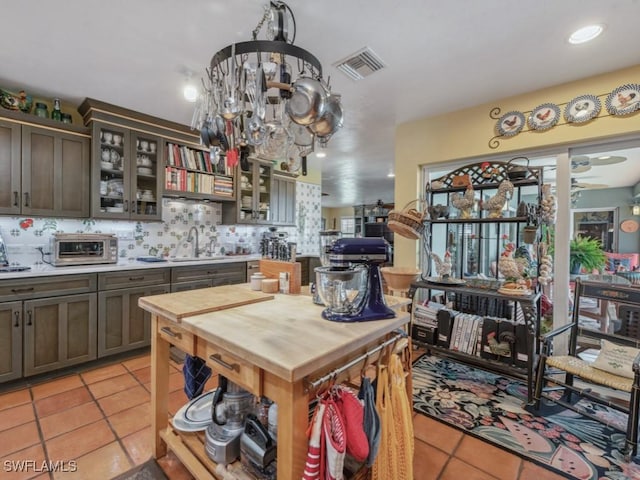 kitchen with light tile patterned flooring, sink, backsplash, ceiling fan, and dark brown cabinetry