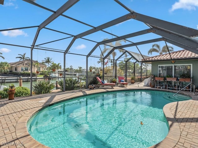 view of pool with a lanai, a patio, and a water view