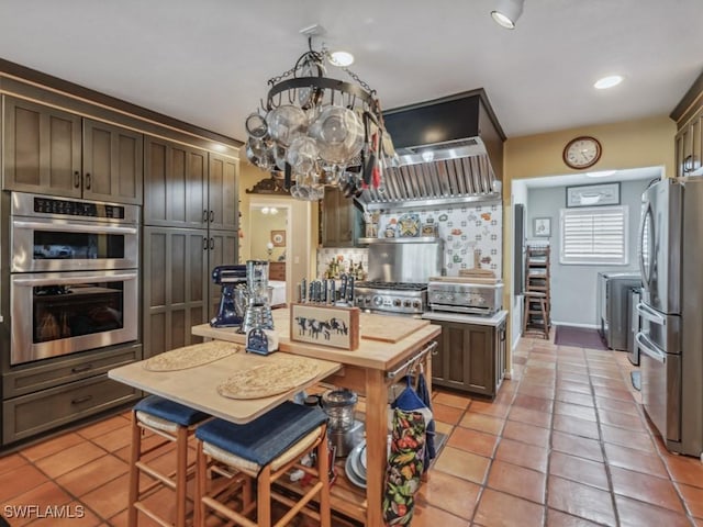 kitchen with light tile patterned floors, premium range hood, stainless steel appliances, a kitchen island, and decorative backsplash