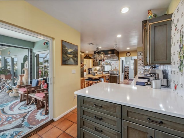 kitchen featuring dark brown cabinetry, kitchen peninsula, decorative backsplash, and light tile patterned floors