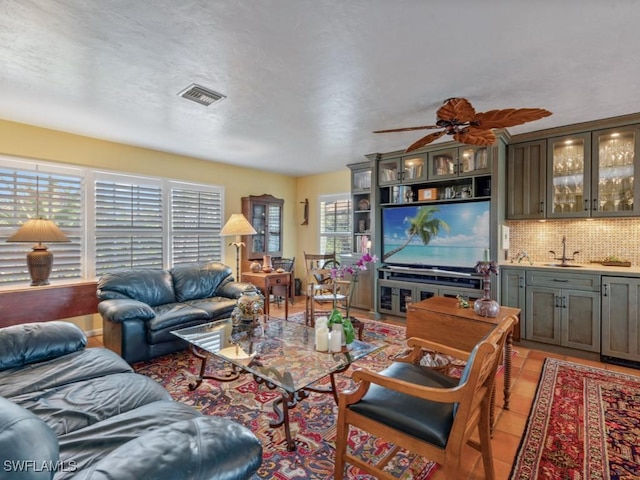 living room featuring ceiling fan, wet bar, and light tile patterned floors