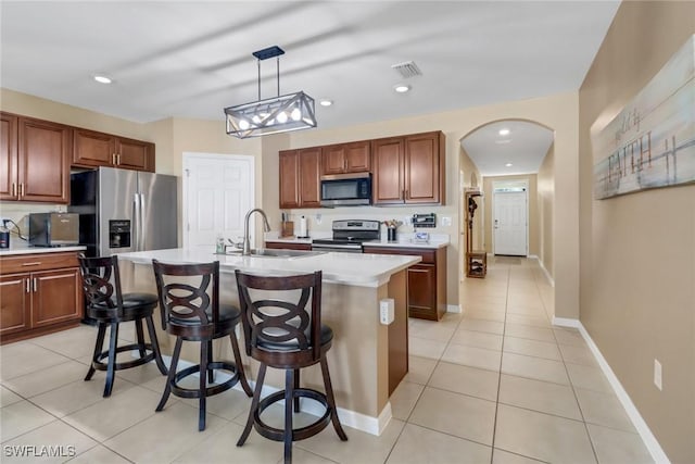 kitchen featuring sink, hanging light fixtures, a center island with sink, light tile patterned floors, and appliances with stainless steel finishes