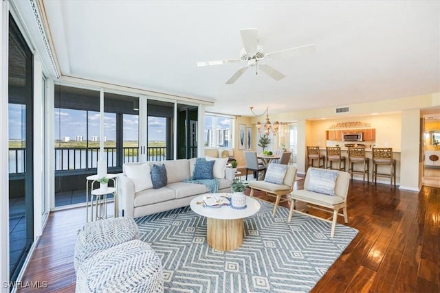 living room featuring a water view, dark hardwood / wood-style floors, and ceiling fan with notable chandelier