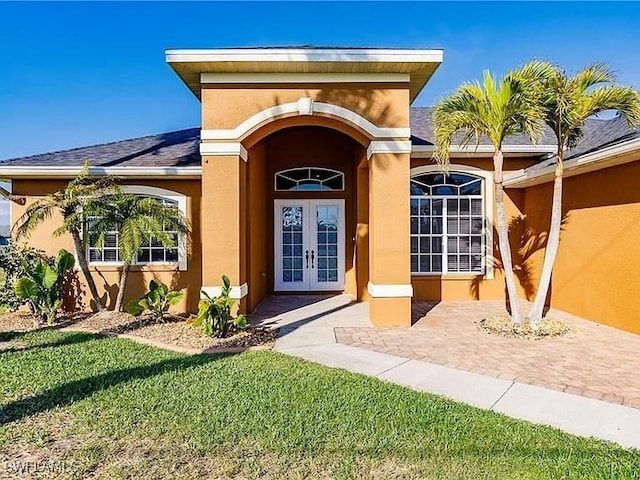 doorway to property with french doors and a lawn