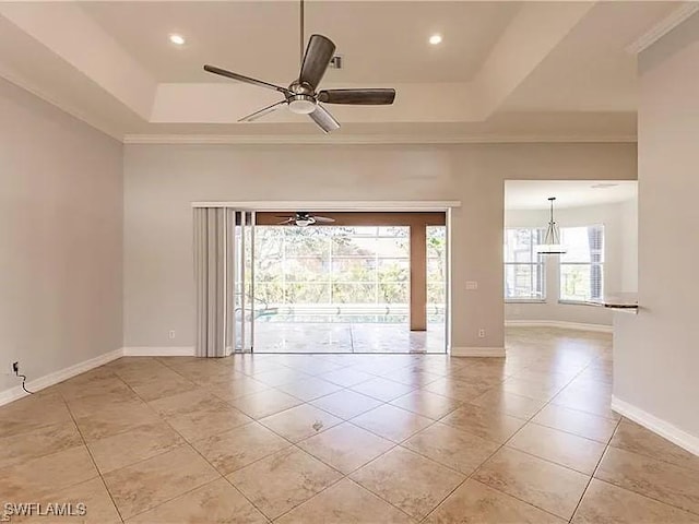 empty room with ornamental molding, light tile patterned floors, ceiling fan, and a tray ceiling