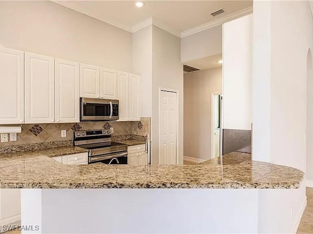 kitchen featuring stainless steel appliances, white cabinetry, light stone counters, and kitchen peninsula