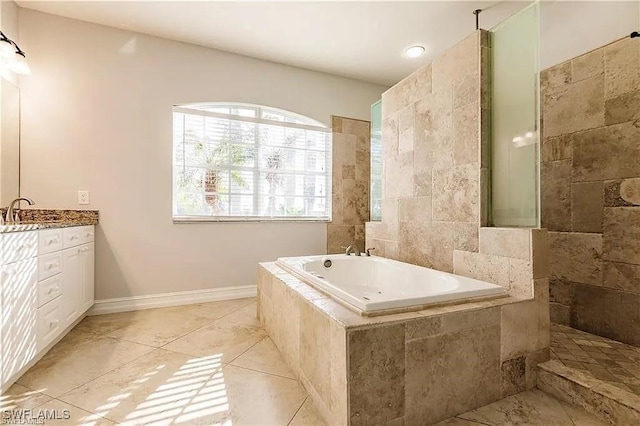 bathroom with vanity, tile patterned flooring, and tiled tub