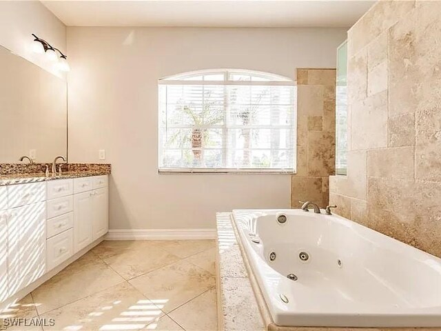 bathroom featuring tile patterned flooring, vanity, and tiled bath