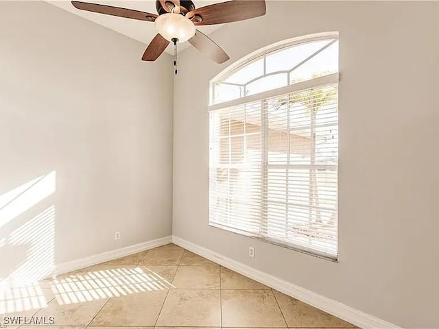 tiled empty room featuring ceiling fan and a wealth of natural light