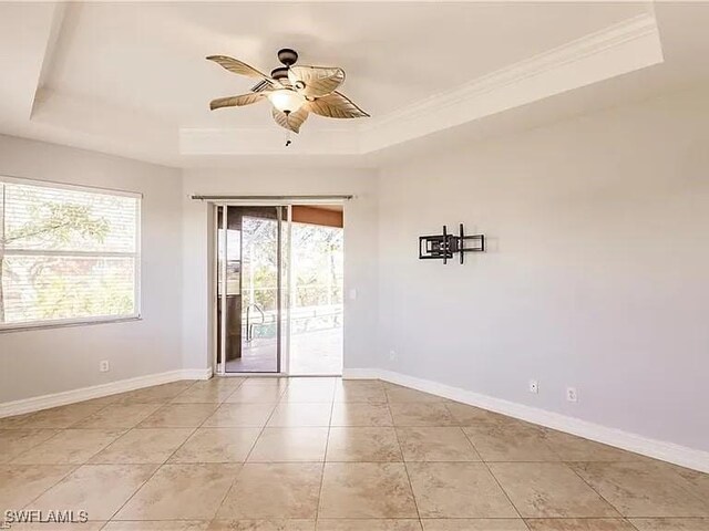 tiled spare room featuring ceiling fan, ornamental molding, and a raised ceiling