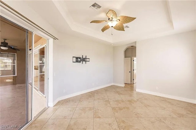 unfurnished room with light tile patterned flooring, ceiling fan, and a tray ceiling