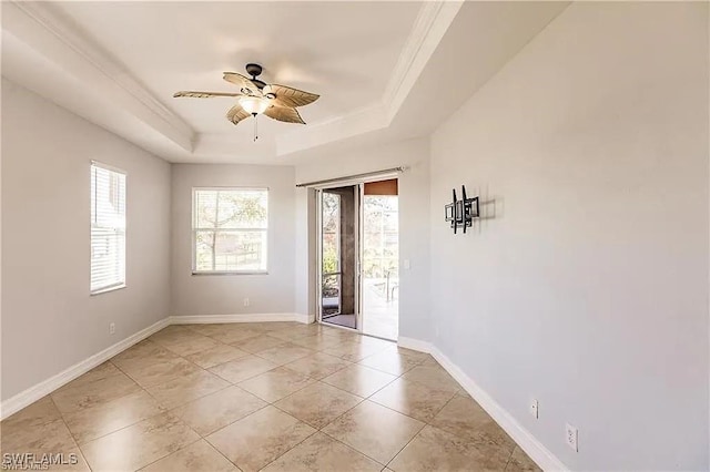 tiled empty room with ornamental molding, a raised ceiling, and ceiling fan