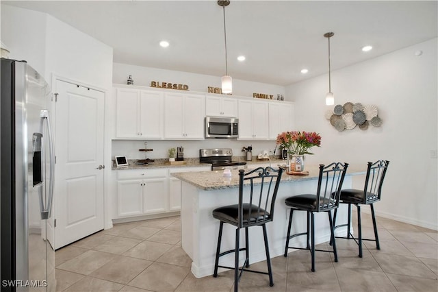 kitchen featuring stainless steel appliances, pendant lighting, white cabinets, and a kitchen breakfast bar