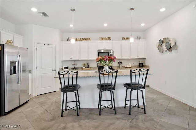 kitchen with decorative light fixtures, white cabinetry, light stone counters, stainless steel appliances, and a center island with sink