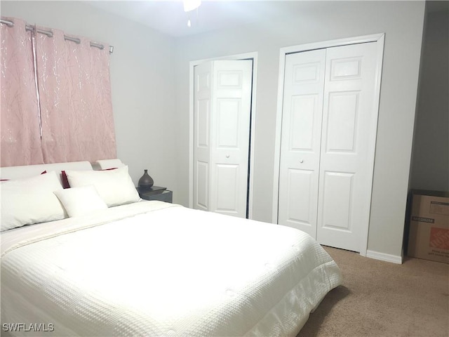 bedroom with multiple closets and light carpet